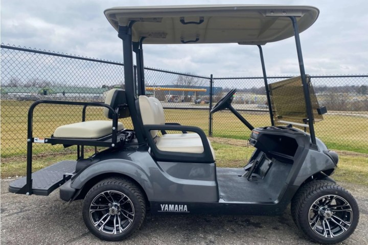 Gray Yamaha golf cart with a canopy parked near a chain-link fence.